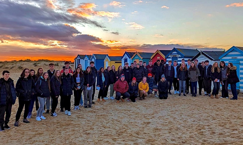 Students in front of a sunset on the beach
